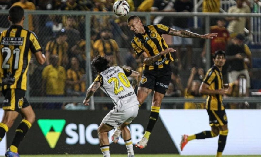 Lance de futebol com jogadores disputando a bola.
