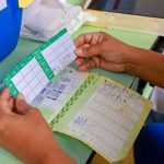 Mãos seguram caderneta de vacinação em consulta médica. Registro de vacinas e saúde.