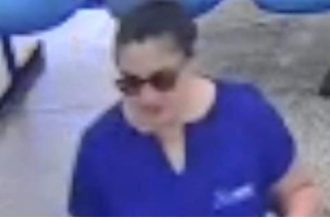 Mulher com óculos escuros vestindo camisa azul, possível suspeita em caso de ameaça.