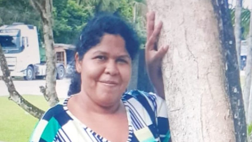 Mulher desaparecida em Manaus, segurando árvore, com expressão sorridente