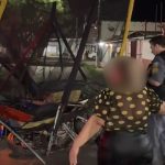 Mulher e policiais em cena de acidente com motocicleta.