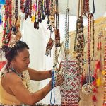 Mulher em feira de artesanato em Manaus, com colares e acessórios coloridos