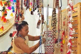 Mulher em feira de artesanato em Manaus, com colares e acessórios coloridos