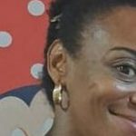 Mulher negra com brincos de argola, em fundo com tema da Minnie.