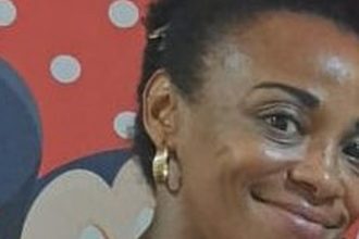 Mulher negra com brincos de argola, em fundo com tema da Minnie.