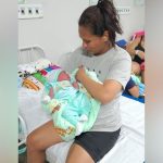 Mulher segura recém-nascido em hospital. Cena de parto no estacionamento do hospital.