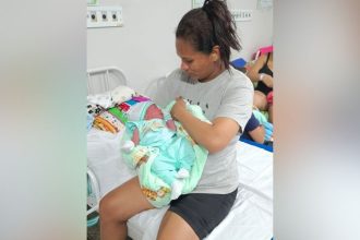 Mulher segura recém-nascido em hospital. Cena de parto no estacionamento do hospital.