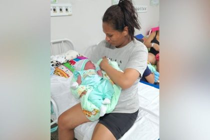 Mulher segura recém-nascido em hospital. Cena de parto no estacionamento do hospital.