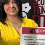 Mulher sorrindo segura mecha de cabelo doada para campanha Outubro Rosa.