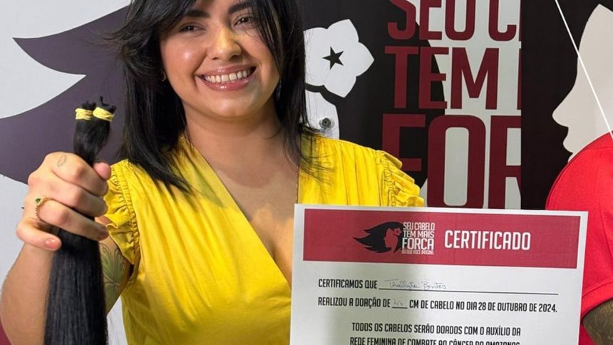Mulher sorrindo segura mecha de cabelo doada para campanha Outubro Rosa.