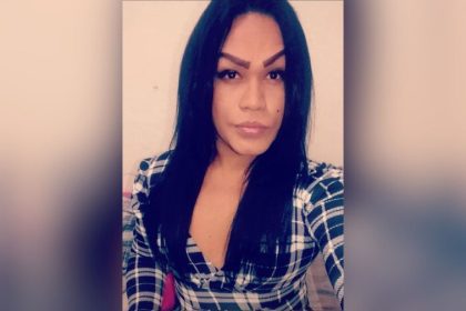 Mulher trans com cabelo preto e camisa xadrez, foto de perfil.