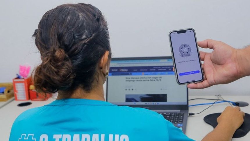 Mulher utilizando computador com celular mostrando Carteira de Trabalho Digital, Sine Manaus.