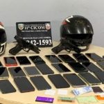Objetos apreendidos em operação policial: capacetes, armas, celulares e documentos.