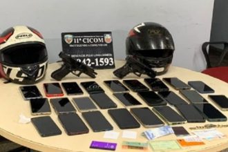 Objetos apreendidos em operação policial: capacetes, armas, celulares e documentos.