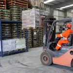 Operador de empilhadeira em armazém da Combitrans, transportando paletes com mercadorias.