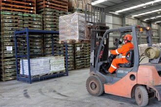 Operador de empilhadeira em armazém da Combitrans, transportando paletes com mercadorias.