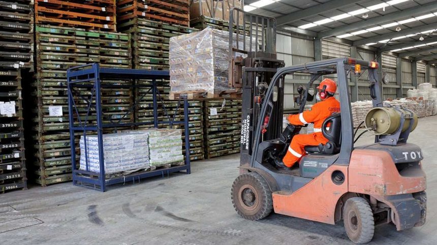 Operador de empilhadeira em armazém da Combitrans, transportando paletes com mercadorias.