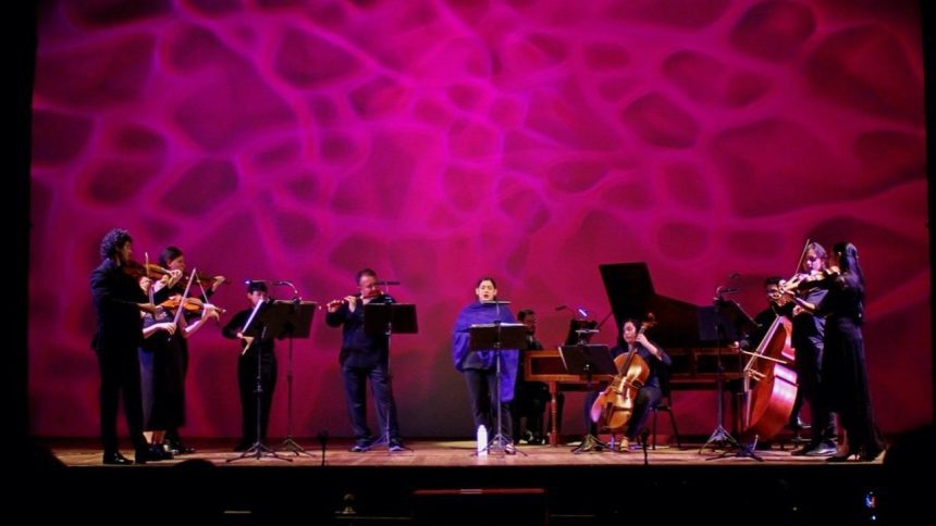 Orquestra Barroca do AM em concerto, com músicos tocando instrumentos de corda e sopro no palco.