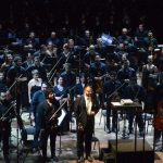 Orquestra no palco do Teatro Amazonas, com maestro em destaque. Apresentação musical 'Assim falou Zaratustra'.