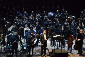 Orquestra no palco do Teatro Amazonas, com maestro em destaque. Apresentação musical 'Assim falou Zaratustra'.