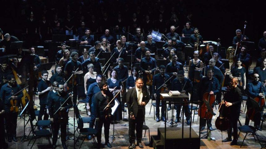 Orquestra no palco do Teatro Amazonas, com maestro em destaque. Apresentação musical 'Assim falou Zaratustra'.
