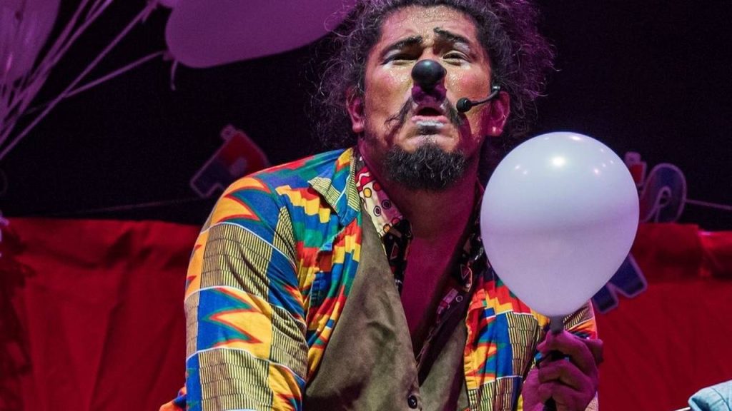 Palhaço com nariz vermelho e balão branco em festival de teatro