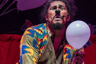 Palhaço com nariz vermelho e balão branco em festival de teatro