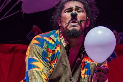 Palhaço com nariz vermelho e balão branco em festival de teatro
