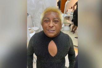 Patixa Teló com cabelo loiro e vestindo um vestido preto com decote.