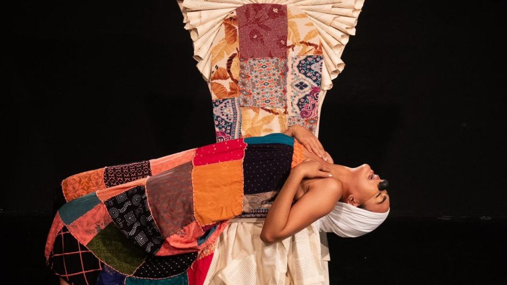 Performance no Festival de Teatro da Amazônia: Atriz com figurino patchwork e adorno.