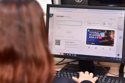 Pessoa acessando plataforma CETAM em computador, com tela mostrando login.