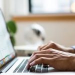 Pessoa digitando em um laptop, com foco nas mãos e teclado