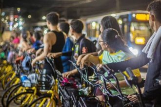 Pessoas alugam bicicletas amarelas em evento Pedala Livre na Ponta Negra, Manaus.