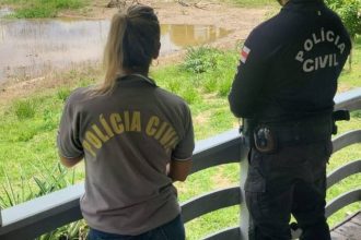 Policiais civis em local de investigação próximo a rio.