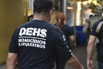 Policial com a inscrição DEHS (Divisão de Homicídios e Sequestros) em ação.