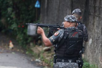 Policial da ROCAM com arma em ação durante operação.