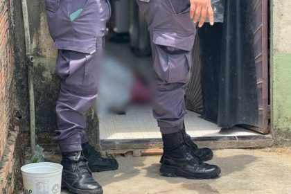 Policial investigando cena de crime em Manaus, com pessoa caída no chão.