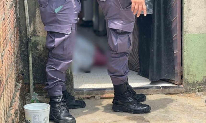 Policial investigando cena de crime em Manaus, com pessoa caída no chão.