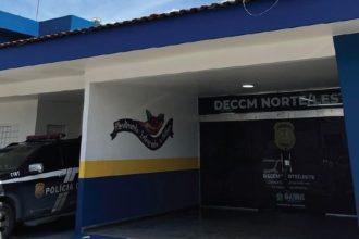 Prédio da DECCM Norte/Leste em Manaus, com carro da polícia e frase 'Atendimento Integrado à Mulher'.