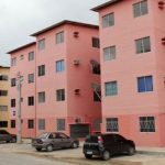 Prédios residenciais coloridos em Manaus, com carros estacionados.