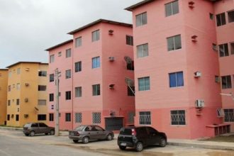 Prédios residenciais coloridos em Manaus, com carros estacionados.