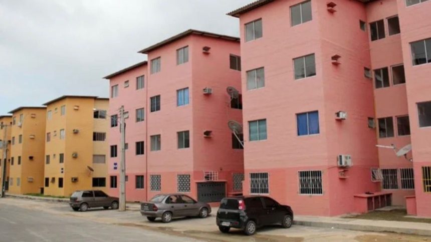 Prédios residenciais coloridos em Manaus, com carros estacionados.