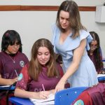 Professora auxiliando aluna em sala de aula durante concurso da Semed.