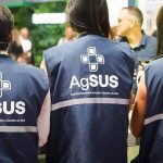 Profissionais de saúde com coletes AgSUS em evento sobre saúde.