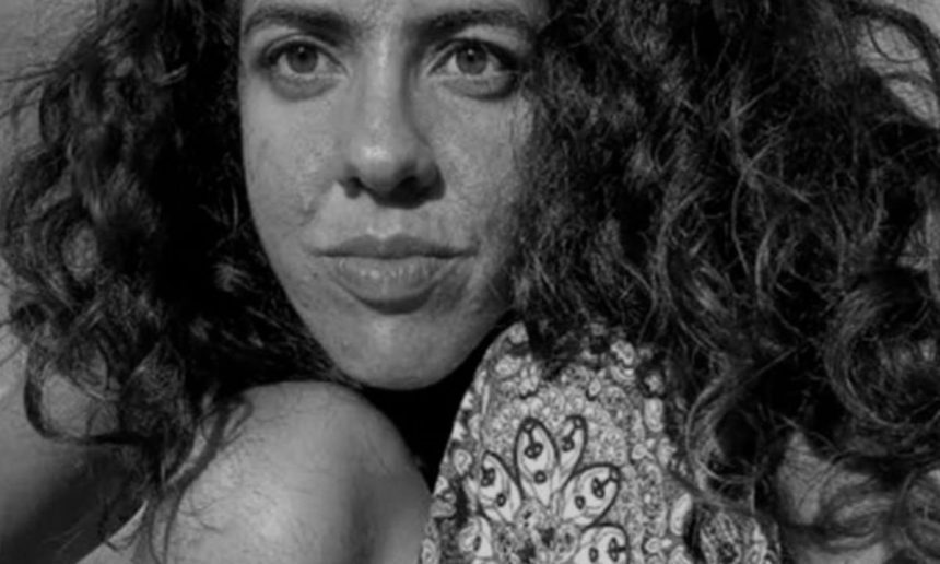 Retrato em preto e branco de uma mulher com cabelo encaracolado e um olhar sério.