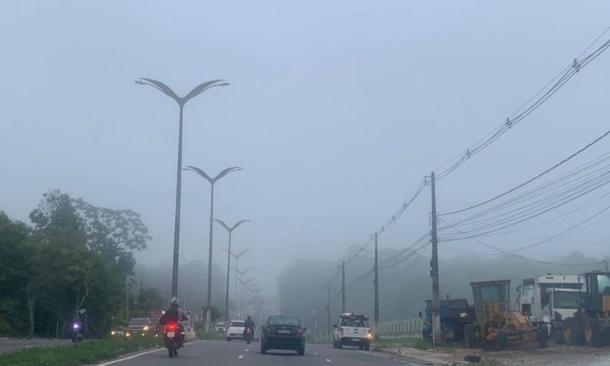 Rodovia com neblina em Manaus, com veículos em movimento e postes de iluminação.