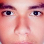 Rosto de homem com olhos escuros em ambiente fechado, possivelmente em um IML.