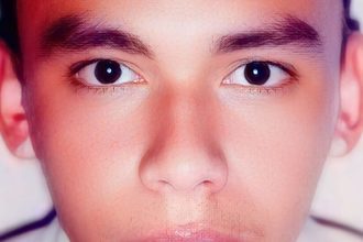 Rosto de homem com olhos escuros em ambiente fechado, possivelmente em um IML.