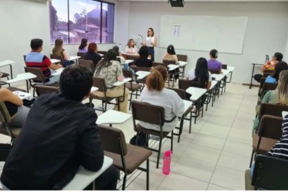 Sala de aula com estudantes e palestrante, possível apresentação sobre concurso.