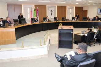 Sessão de julgamento com juízes e advogados em plenário.